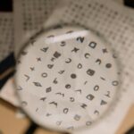 pexels-photo-7319085-7319085 Magnifying glass revealing cryptic symbols on paper, ideal for mystery themes.
